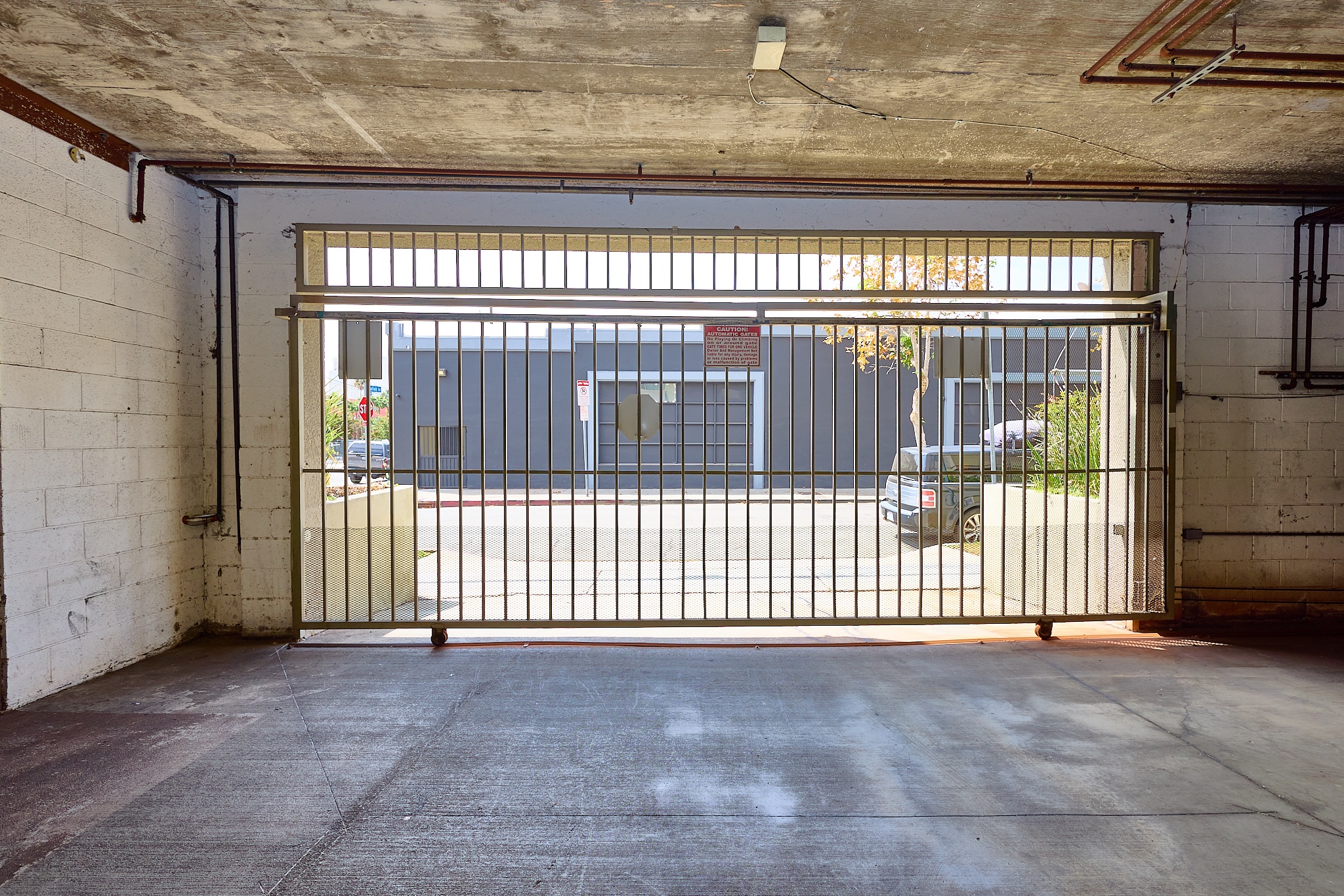 A car is parked behind a gate in a parking garage.
